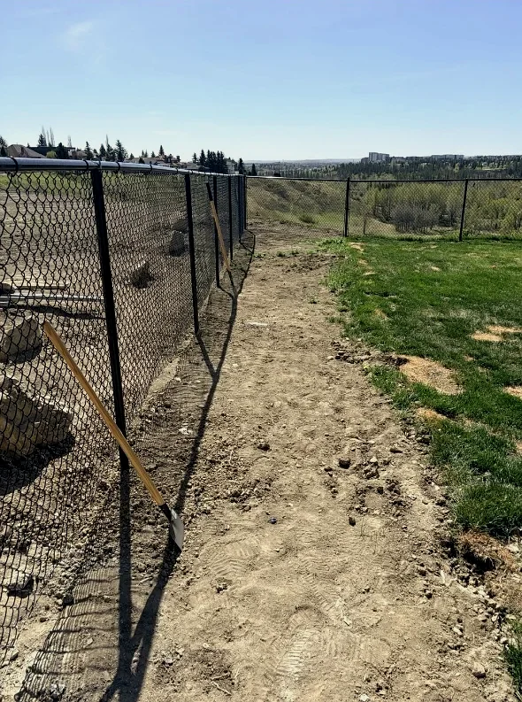 Torn-up fence line with bare dirt overlooking the valley; before landscaping, Calgary