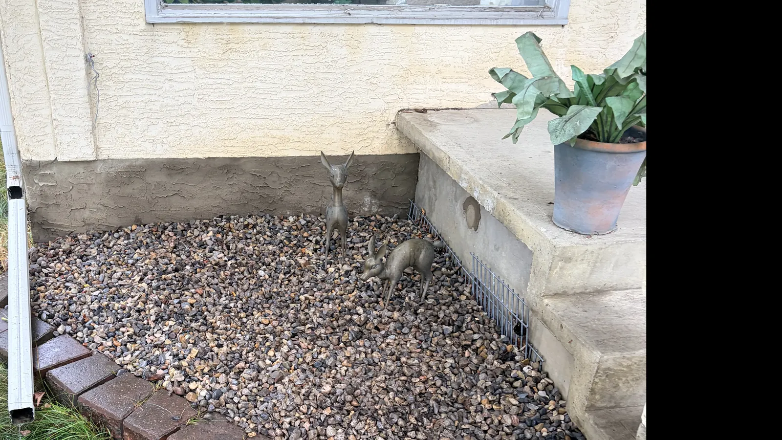 Finished decorative rock in a compact corner bed beside concrete steps and a curved brick border