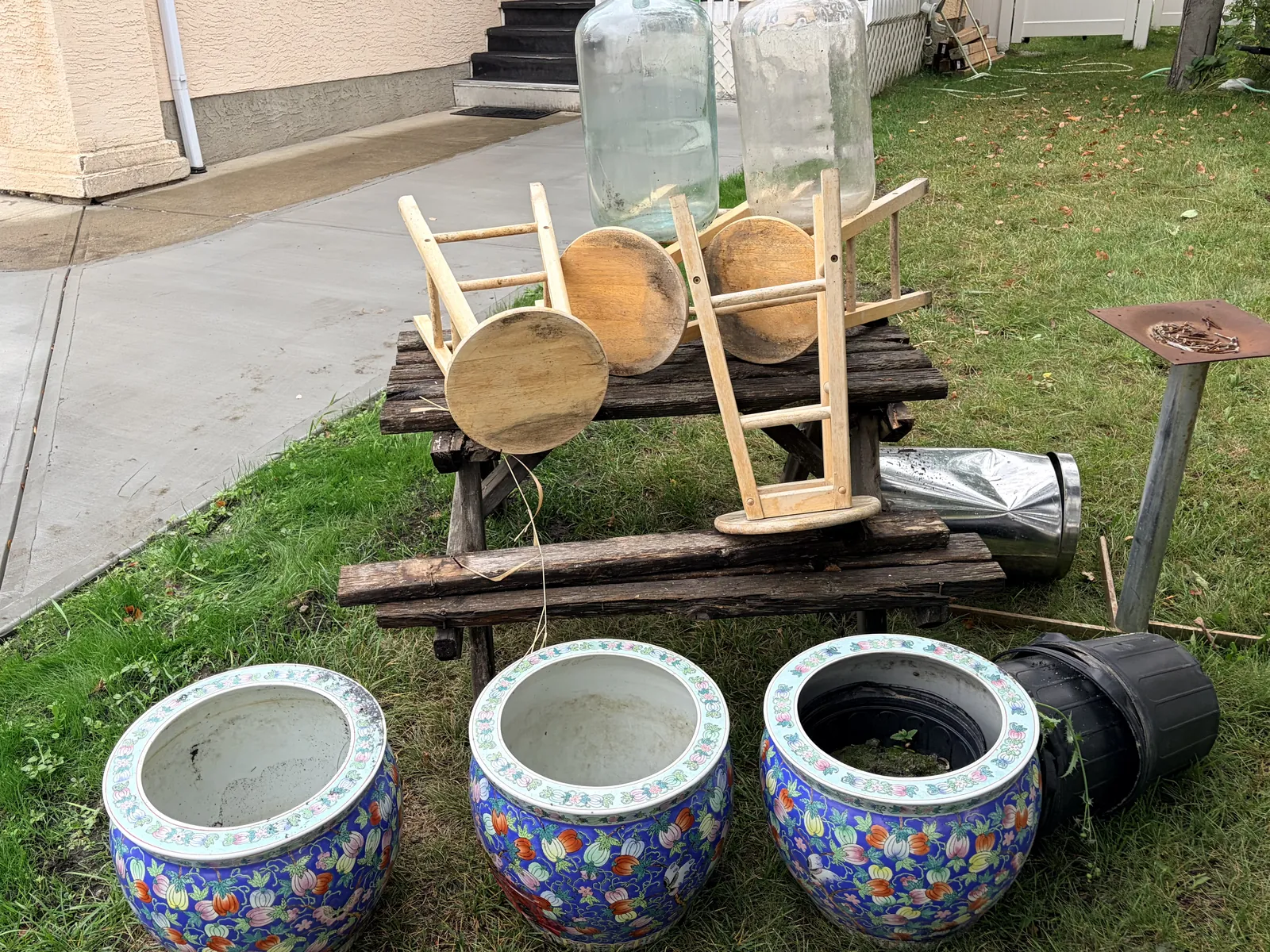 Large planters, wooden stools and outdoor items grouped together on a lawn for hauling pickup