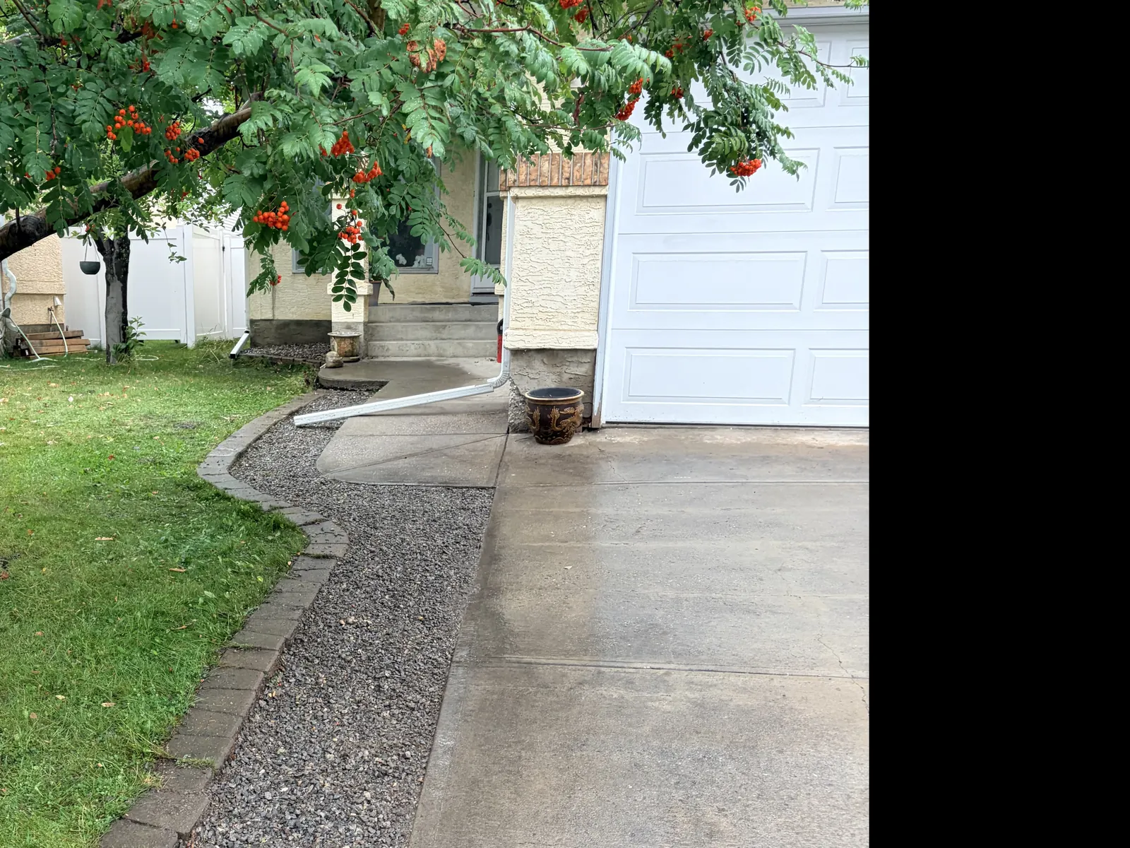 Long decorative rock border following a driveway and curved brick lawn edge at a Calgary home