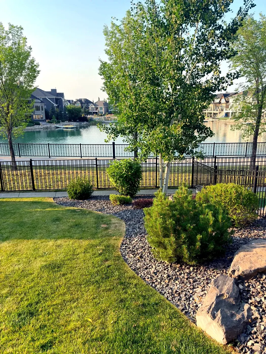 Manicured lakefront yard with curved lawn edge and slate rock beds; Calgary lake community
