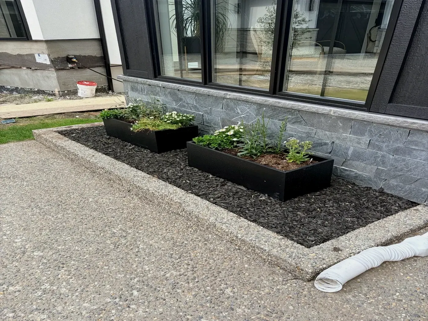 Black mulch bed with modern planters at a Calgary home; installed by Edge Property Services